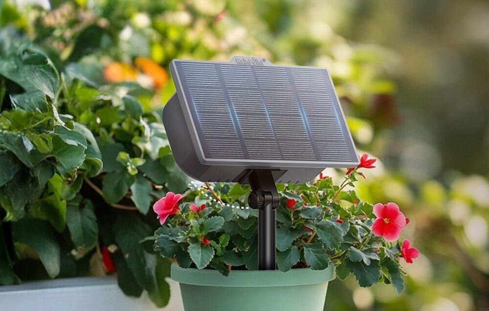 Zestaw do nawadniania RAINPOINT ITP138SP+DIK10, czas podlewania, częstotliwość, regulacja, wygoda, Panel solarny podłączony do kilku doniczek z roślinami ustawionych na stole w ogrodzie.