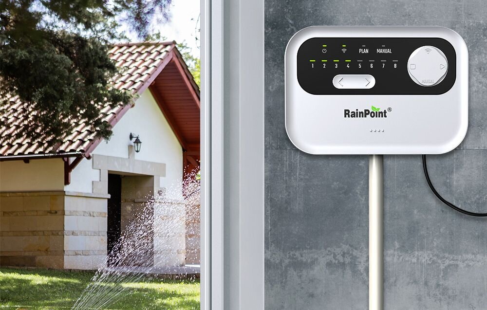 Sterownik nawadniania RAINPOINT HIC801W, czujnik deszczu, wilgotność gleby, automatyka, oszczędność, Sterownik zraszaczy RainPoint na ścianie obok domu i działającego zraszacza ogrodowego.