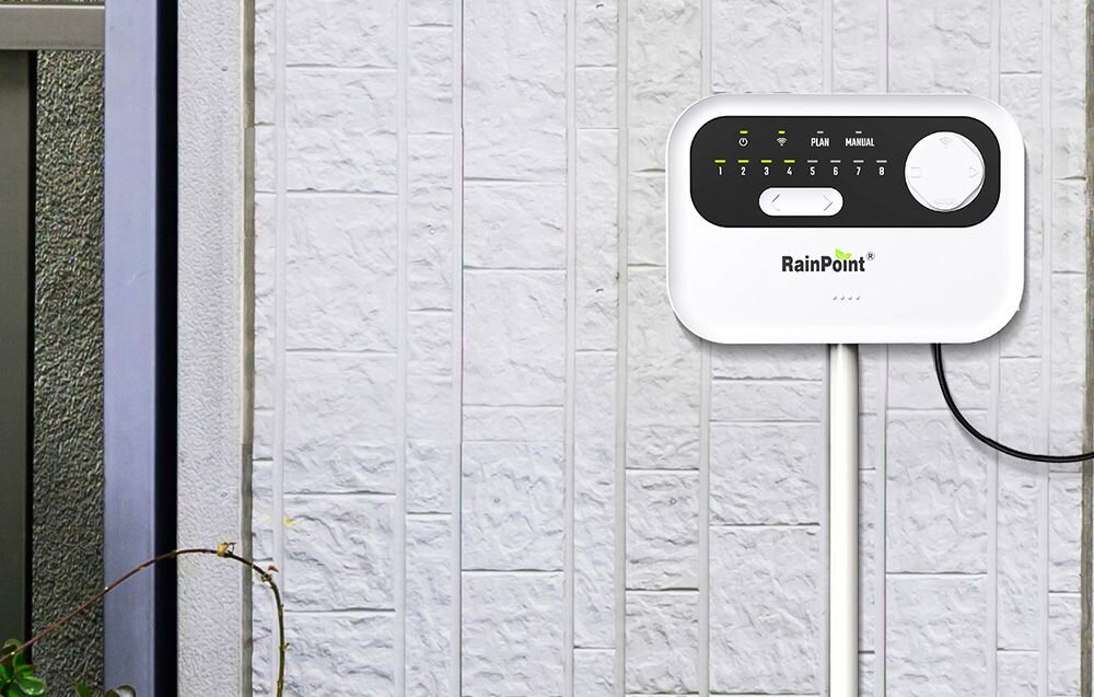 Sterownik nawadniania RAINPOINT HIC801W, automatyczne cykle, kolejność stref, testowanie, kontrola, Sterownik zraszaczy RainPoint zamontowany na ścianie budynku z podłączonym przewodem.