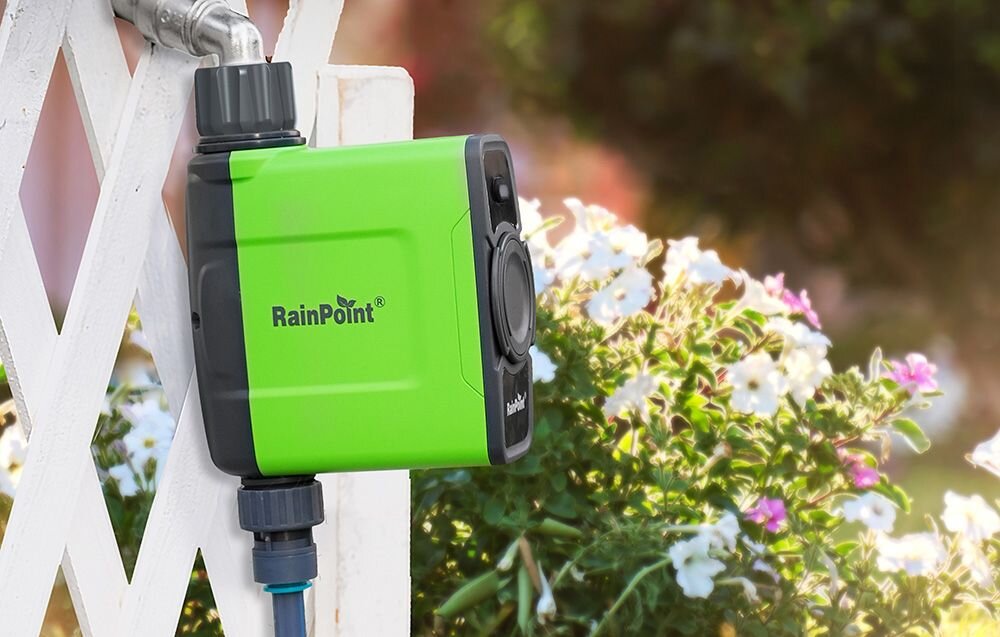 Sterownik nawadniania RAINPOINT HTV145FRF+HWG023WBRF, aplikacja, RainPoint, zdalne sterowanie, smart home, Sterownik nawadniania RainPoint zamontowany przy ogrodzeniu obok kwiatów.
