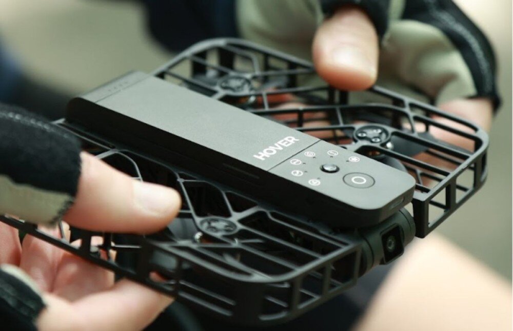 Dron HOVERAIR X1 Combo Plus Czarny dron z widocznymi śmigłami wewnątrz klatki ochronnej