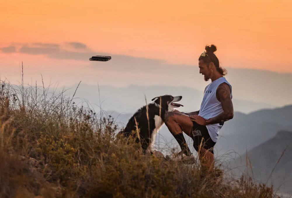 Dron HOVERAIR X1 Combo Plus Mężczyzna z psem obserwujący drona na tle górskiego krajobrazu