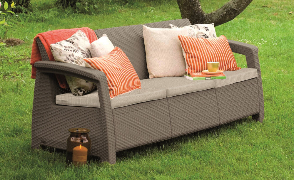 Sofa ogrodowa KETER Cofru Love Seat 3 osobowa Grafitowy sofa na trawie w tle drzewa i rośliny prosty montaż system JUST CLICK AND GO montaż na zatrzaski intuicyjny w obsłudze nie wymaga użycia dodatkowych narzędzi Intuicyjny system łączenia szybkie i proste złożenie sofy