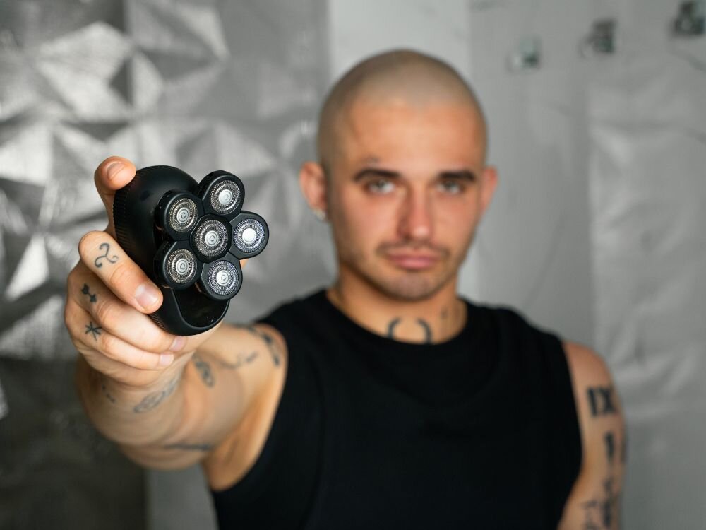 Mężczyzna o ogolonej głowie prezentuje golarkę Shav Crowner w dłoni