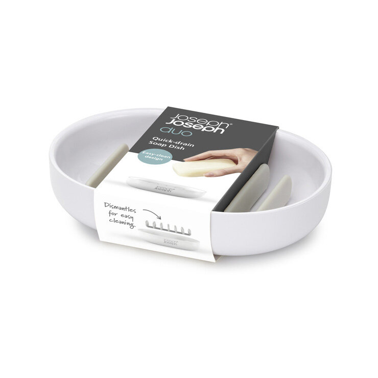 Biała mydelniczka z minimalistycznym designem, z opakowaniem zawierającym tekst: \'Joseph Joseph Duo Quick-drain Soap Dish\'. Widoczna jest również grafika przedstawiająca mydelniczkę z mydłem oraz napis \'Dismantles for easy cleaning\'.