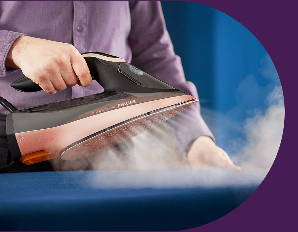 Osoba trzyma żelazko, z którego wydobywa się para. Na żelazku widoczny jest napis \'Azur 8000 Series PHILIPS\'.