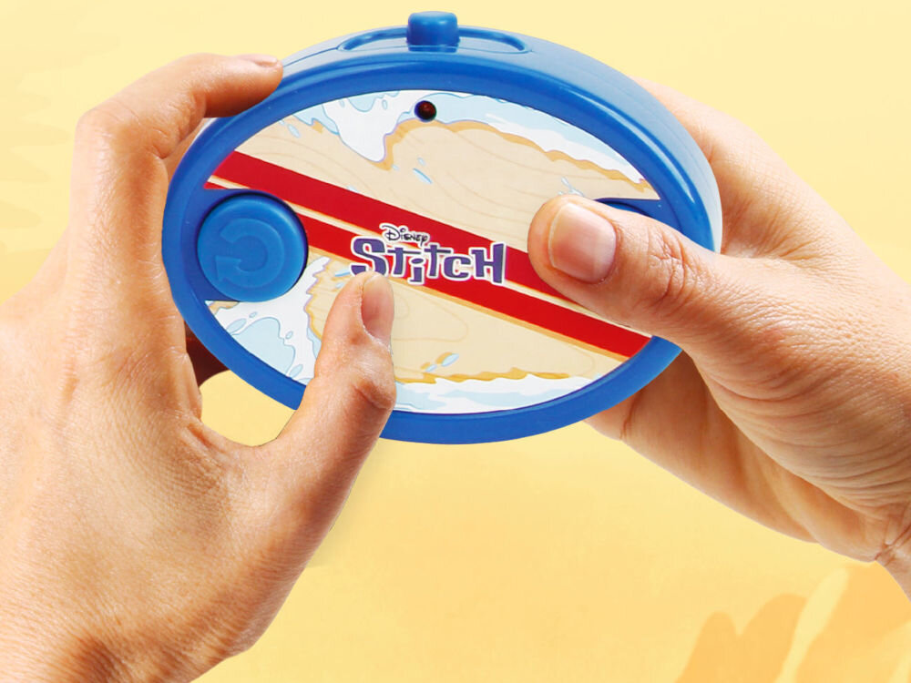 Pilot 2,4 GHz Stitch Disney Jada Toys zdalne sterowanie baterie R6 R03 zabawka dla dzieci - Dwie dłonie trzymające owalny, niebieski pilot zdalnego sterowania do pojazdu Stitcha. W centralnej części pilota, w jasnym polu przypominającym deskę surfingową z czerwonym pasem, znajduje się logo Disney'a i napis Stitch. Pilot ma dwa przyciski sterujące: duży okrągły po lewej i mniejszy po prawej