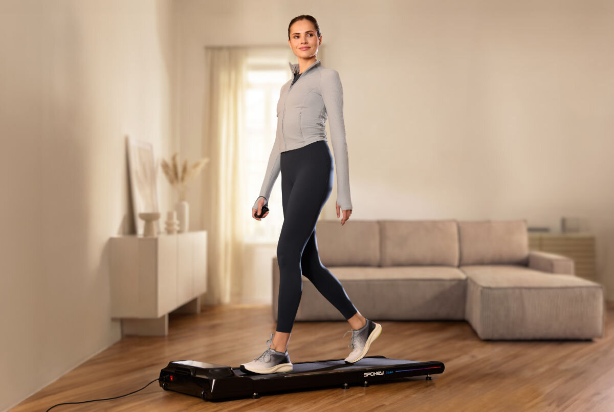 Bieżnia elektryczna SPOKEY Dash 932W 6 km/h, przerwa, wznowienie, parametry, wygoda, Kobieta chodzi na kompaktowej bieżni Spokey w salonie