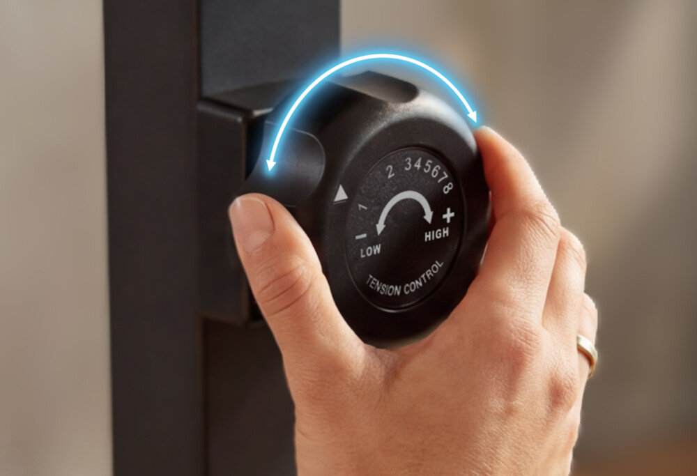 Rower magnetyczny SPOKEY Dust zbliżenie na pokrętło do regulacji osoba trzyma pokrętło w dłoni manualna regulacja oporu w 8-stopniowym zakresie obciążenie będzie dopasowane do Twoich potrzeb i umiejętności