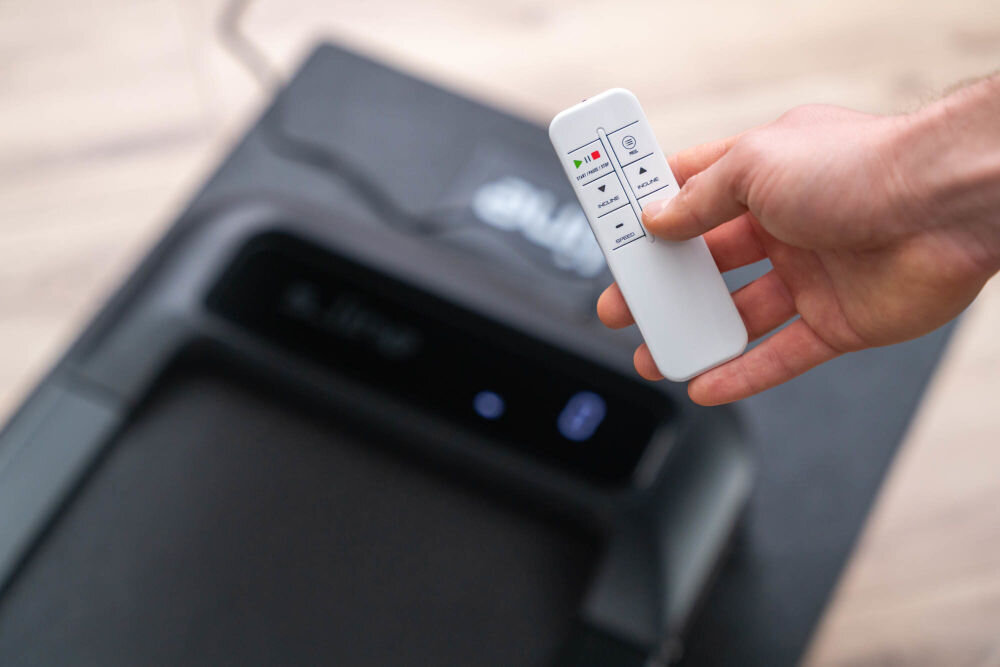 Bieżnia elektryczna S_LINE Paddy 920W 6 km/h Pilot do sterowania bieżnią S-Line Paddy w białej obudowie z czytelnymi przyciskami do zmiany prędkości, kąta nachylenia oraz funkcji start/stop.