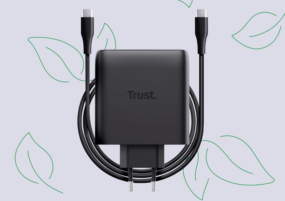 Zasilacz do laptopa TRUST Maxo 25527 100W Czarny ładowarka z podłączonymi dwoma czarnymi kablami USB-C, otoczona zielonymi symbolami liści na jasnym tle