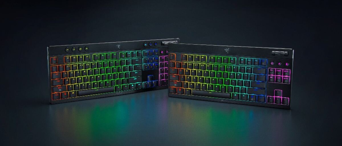 Dwie klawiatury z podświetleniem RGB w różnych kolorach, umieszczone na ciemnym tle. Na klawiaturach widoczne jest logo producenta.