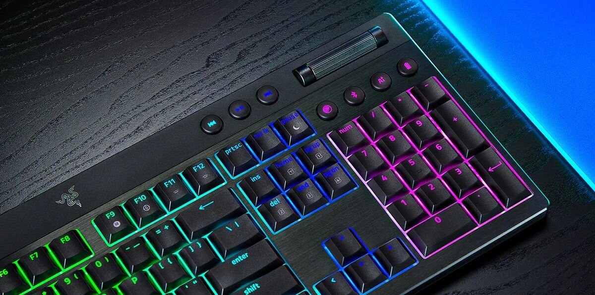 Klawiatura z podświetleniem RGB, widoczne klawisze funkcyjne i numeryczne. Na obudowie znajduje się logo w kształcie trzech węży.