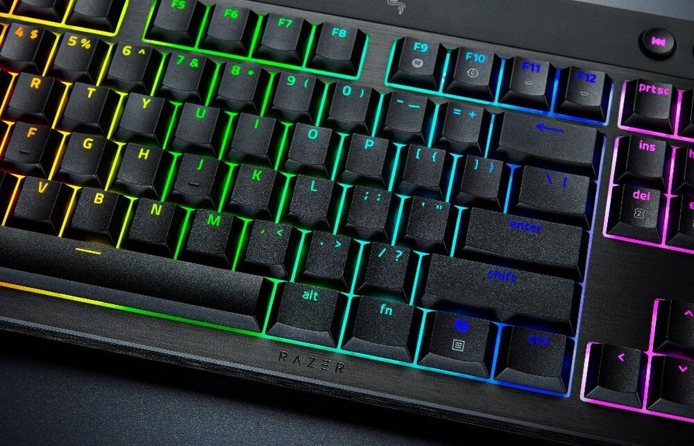 Klawiatura mechaniczna z podświetleniem RGB, widoczne klawisze funkcyjne i strzałki. Na dolnej części klawiatury znajduje się logo \'RAZER\'.
