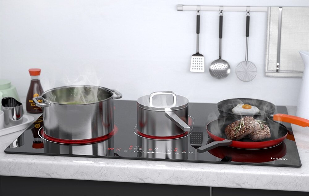 Płyta ceramiczna ISEASY LT5-02 Na płycie grzewczej jednocześnie gotują się potrawy w garnkach i na patelni, z widoczną parą unoszącą się znad dań. W tle widać kuchenne akcesoria wiszące na relingu różne naczynia stal żeliwo ceramika