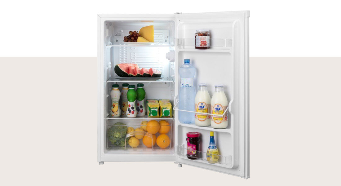 Lodówka GODDESS RME085GW8SSE Zdjęcie przedstawia otwartą lodówkę z uporządkowanym wnętrzem, wypełnionym napojami, owocami i produktami spożywczymi rozmieszczonymi na półkach i w drzwiach. Jasne oświetlenie ułatwia widoczność zawartości pojemność 88l szklane półki szuflada warzywa półki drzwi