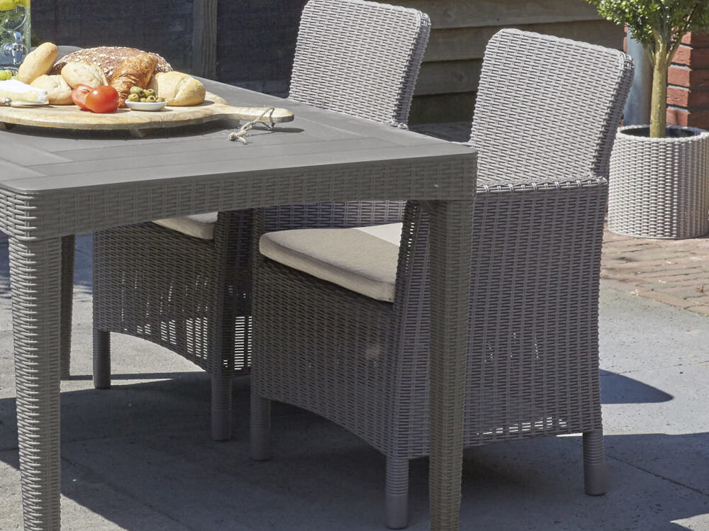 Zestaw mebli ogrodowych KETER Trenton Balcony Capuccino fotele na tarasie obok stół na stole przekąski w tle dom wymiary foteli 63 x 60 x 85 cm wymiary stolika 39 x 39 x 42 cm lekka forma rattanowa faktura łatwe do przenoszenia i ustawienia