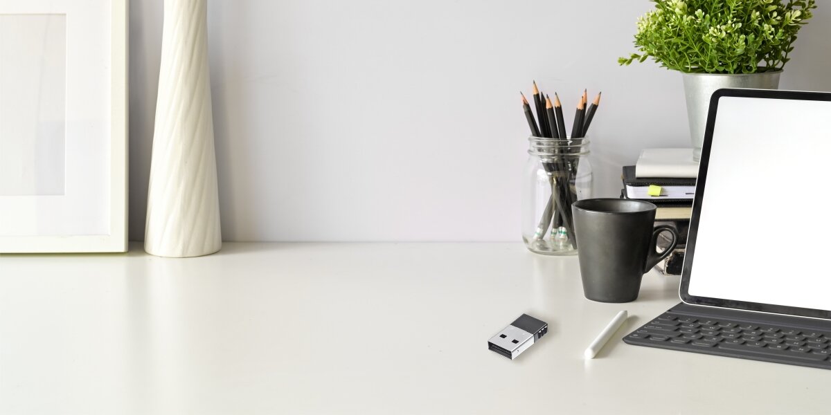 Adapter Bluetooth HAMA 53313 Zbliżenie na dłoń trzymającą czarny transmiter FM marki Hama zintegrowany z ładowarką samochodową, wyposażony w wyświetlacz LED oraz dwa porty USB.