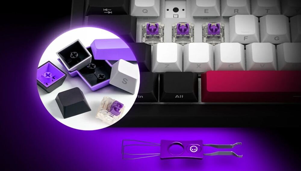 Obraz przedstawia klawiaturę z białymi i czarnymi klawiszami oraz fioletowymi przełącznikami. W okrągłym powiększeniu widoczne są fioletowe i czarne nakładki na klawisze oraz narzędzie do ich zdejmowania.