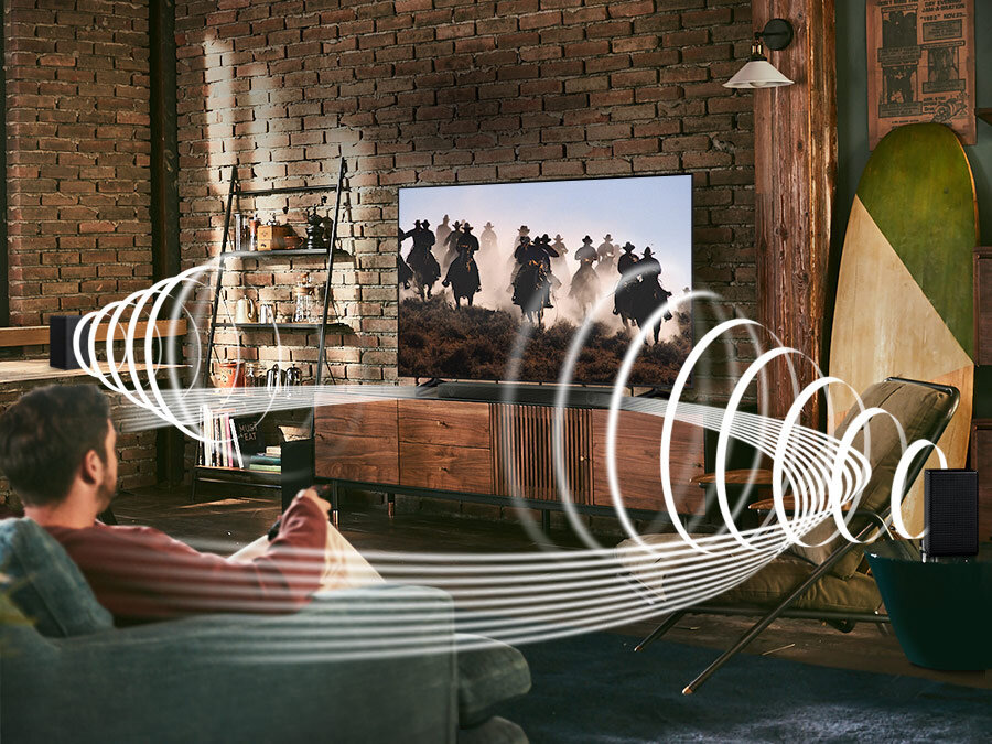 phputnfyy pl-feature-more-sound-without-the-wire-532169627 A man enjoys racing content on his TV. Samsung Wireless Rear Speaker Kit and Soundbar create Immersive surround sound. Toggle button is shown. HW-B550/EN