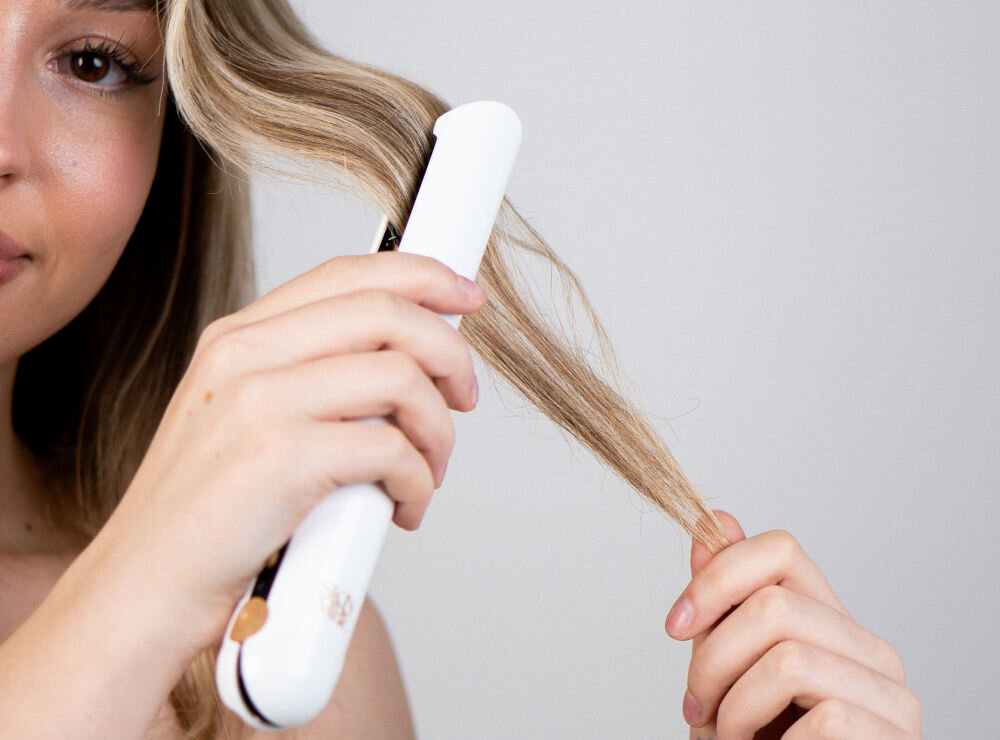 Prostownica SKINVIBE Luna Miniwireless SV-003WH Biały 210 stopni kobieta przejeżdża prostownicą po blond włosach wszechstronne narzędzie profesjonalna stylizacja włosów zaokrąglona obudowa precyzyjne rozprowadzanie ciepła unikalny styl gładkie lśniące pasma lekkie niedbałe fale sprężyste loki pełne objętości