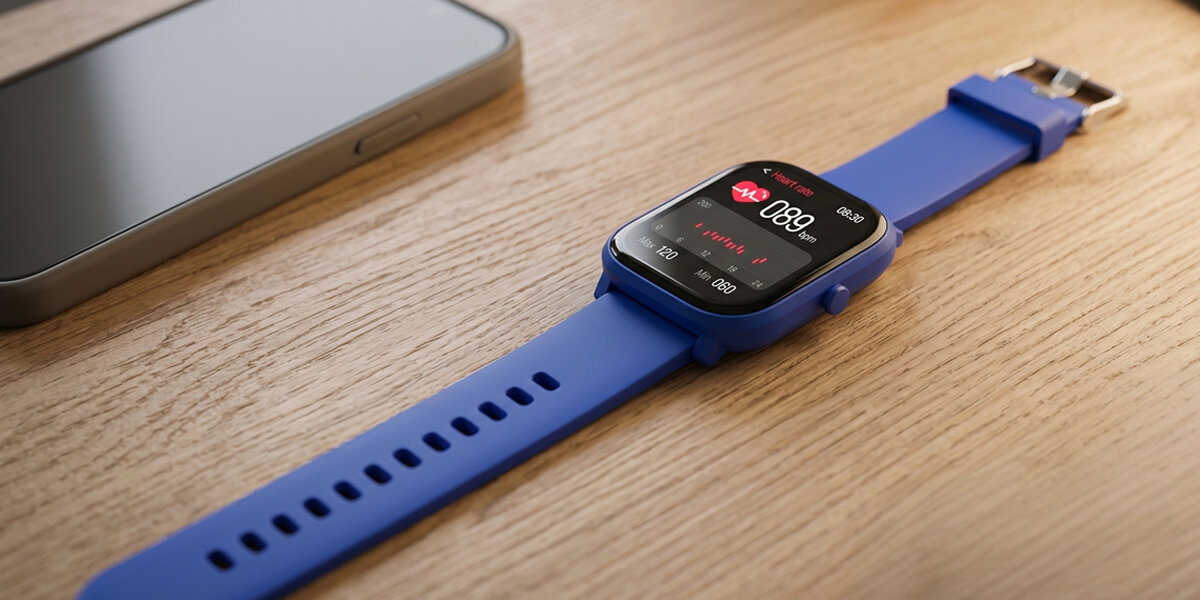 Smartwatch BT Denver SWK-120BU leży obok telefonu, pokazując pomiar tętna na ekranie.