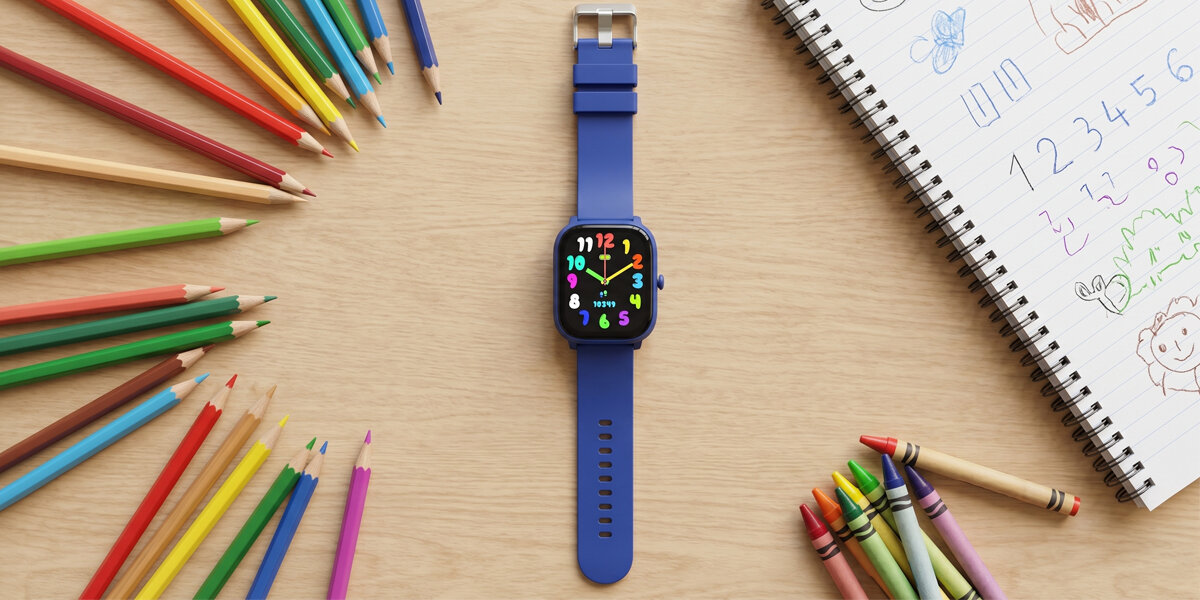 Dziecięcy smartwatch Denver SWK-120BU wśród kredek i zeszytu, z kolorową tarczą.