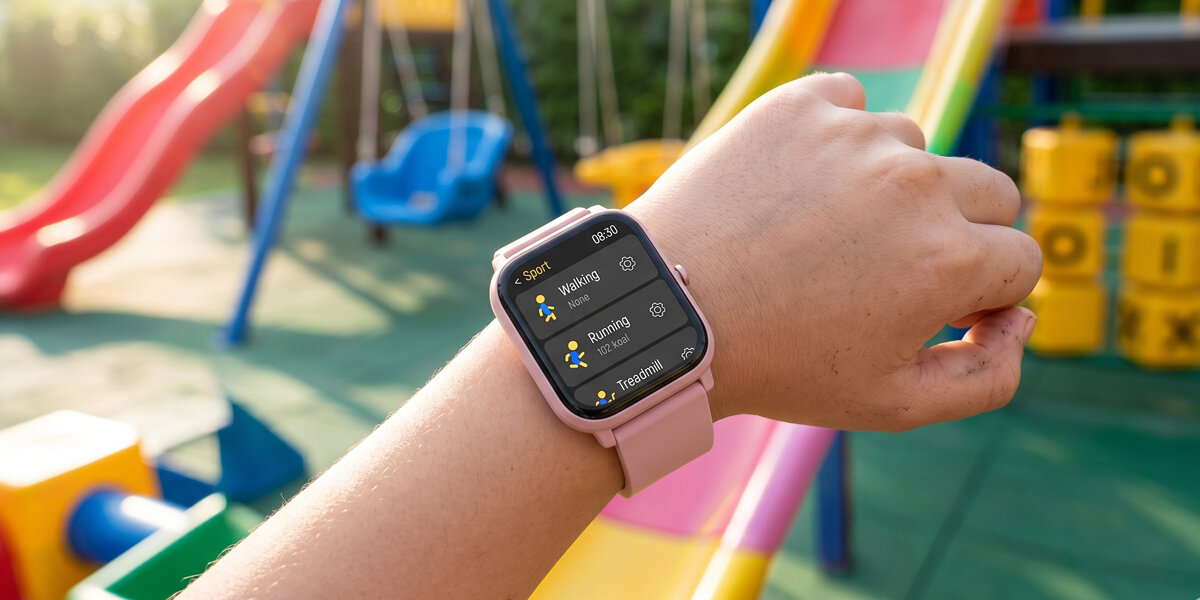 Osoba nosi różowy smartwatch z wyświetlaczem pokazującym różne tryby sportowe, takie jak Walking, Running i Training. W tle widoczne są kolorowe elementy placu zabaw.