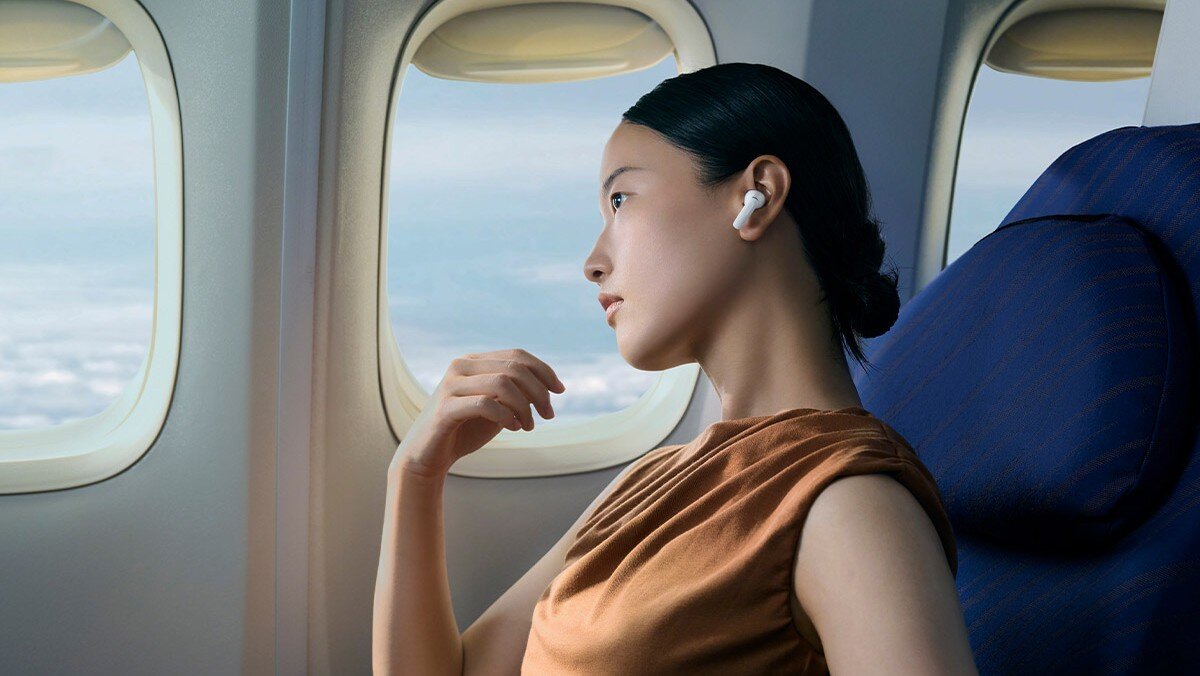 OPPO Enco X3s ANC Dynaudio profil dźwięku scena muzyczna, Kobieta siedząca w samolocie z założonymi słuchawkami OPPO