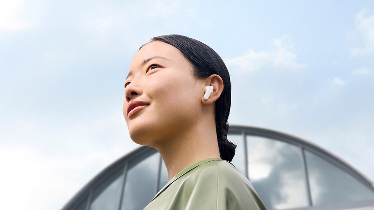 OPPO Enco X3s ANC Golden Sound 2.0 spersonalizowany profil audio, Kobieta w słuchawkach na tle nowoczesnego budynku