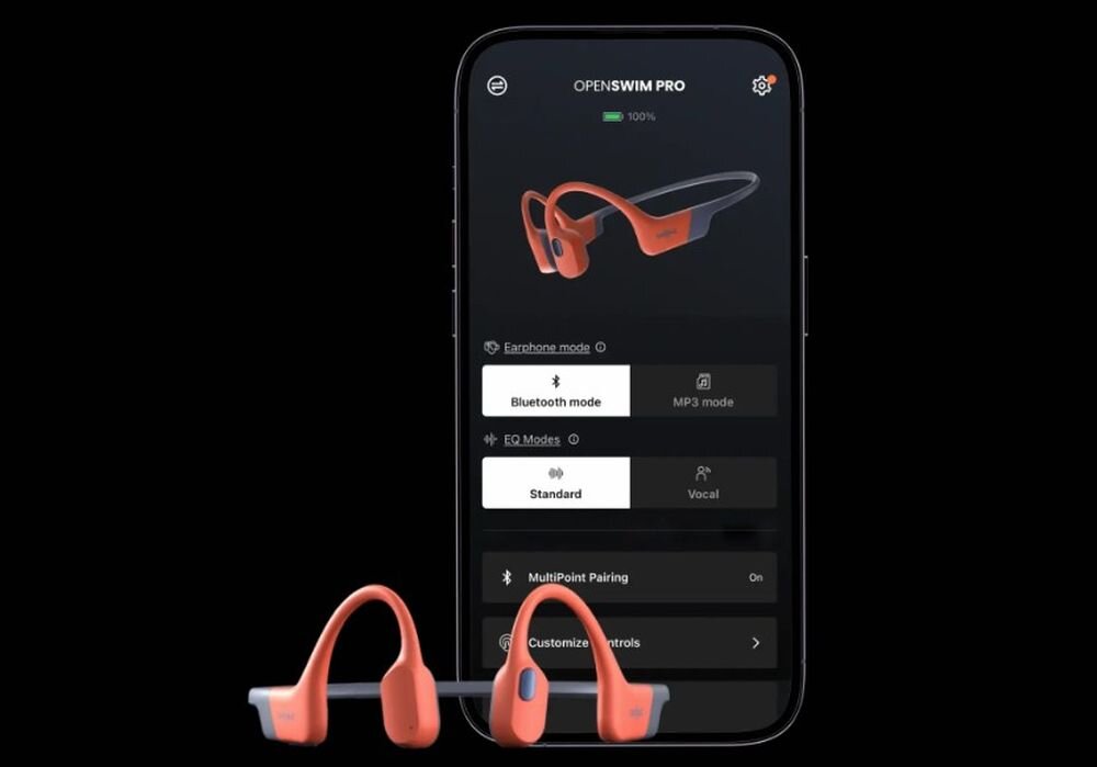 Słuchawki SHOKZ OpenSwim Pro aplikacja Shokz App zarządzanie trybami i baterią, słuchawki kostne od frontu  na czarnym tle, smartfon