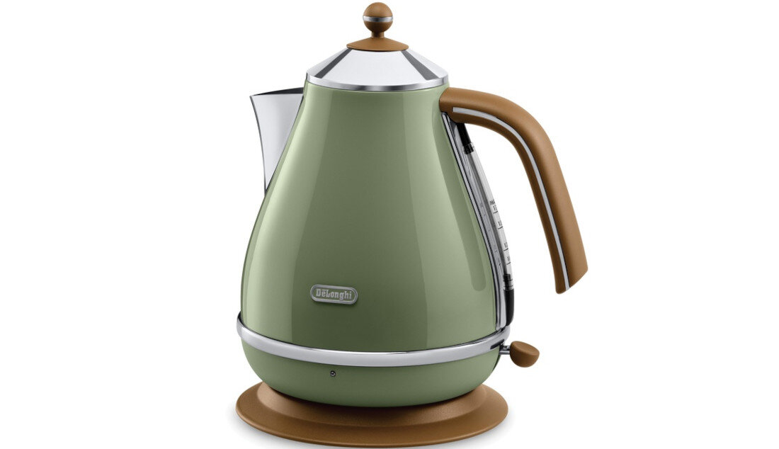 Zielony czajnik elektryczny z brązowym uchwytem i podstawą, posiada chromowane wykończenia. Na przedniej części widoczne jest logo \'DeLonghi\'.