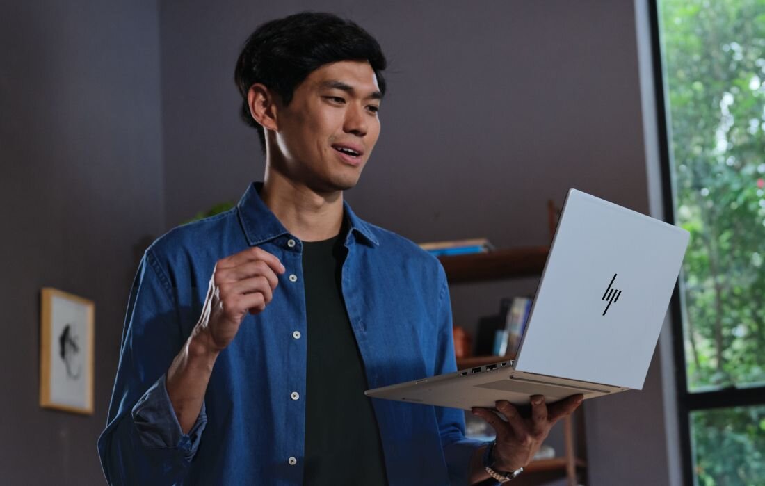 Osoba trzyma lekki laptop HP EliteBook jedną ręką w pomieszczeniu domowym, prezentując mobilność urządzenia do pracy. - Chłodzenie HP Smart Sense