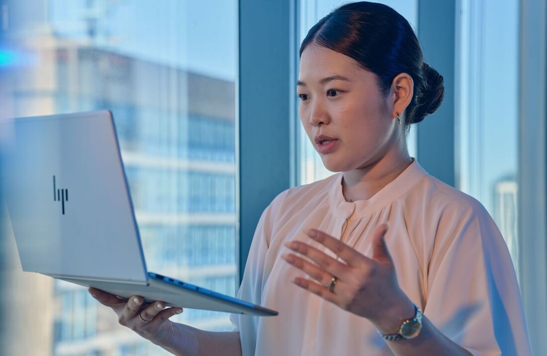 Osoba korzysta z laptopa HP EliteBook 8 G1i podczas wideorozmowy w nowoczesnym biurze z dużym oknem – procesor Intel Core Ultra 7 255U ekran 14 cali WUXGA bateria 62 Wh