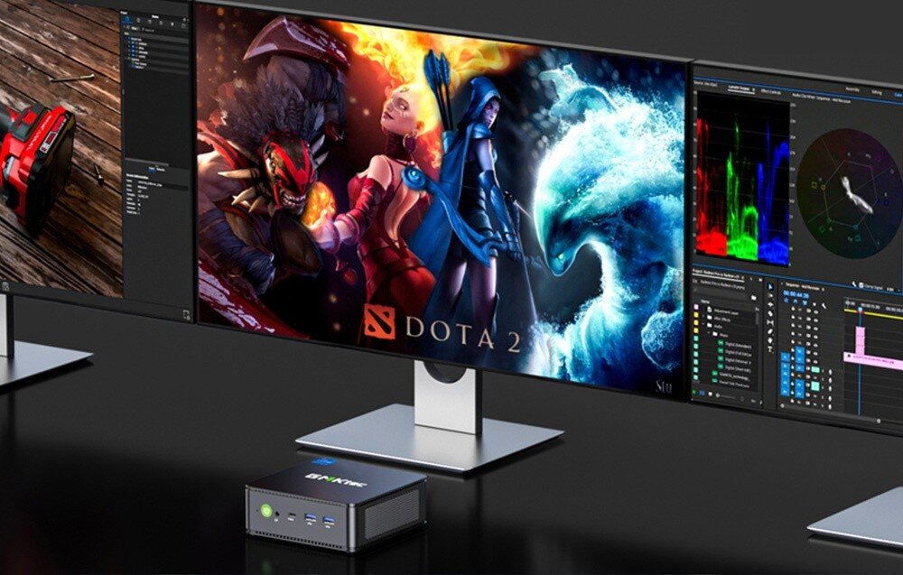Komputer GMKTEC K7 Plus Komputer stojący przed szerokim monitorem, na ekranie widoczna gra 'Dota 2' oraz inne aplikacje, obok kolejne monitory z dodatkowymi panelami, cechy, zalety, wielkość, podzespoły