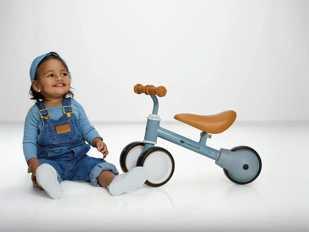 Kinderkraft rowerek biegowy CUTIE LIGHT BLUE pierwsza jazda niebieski rowerek siodełko gumowe uchwyty czarno białe koła obok siedzi maluch