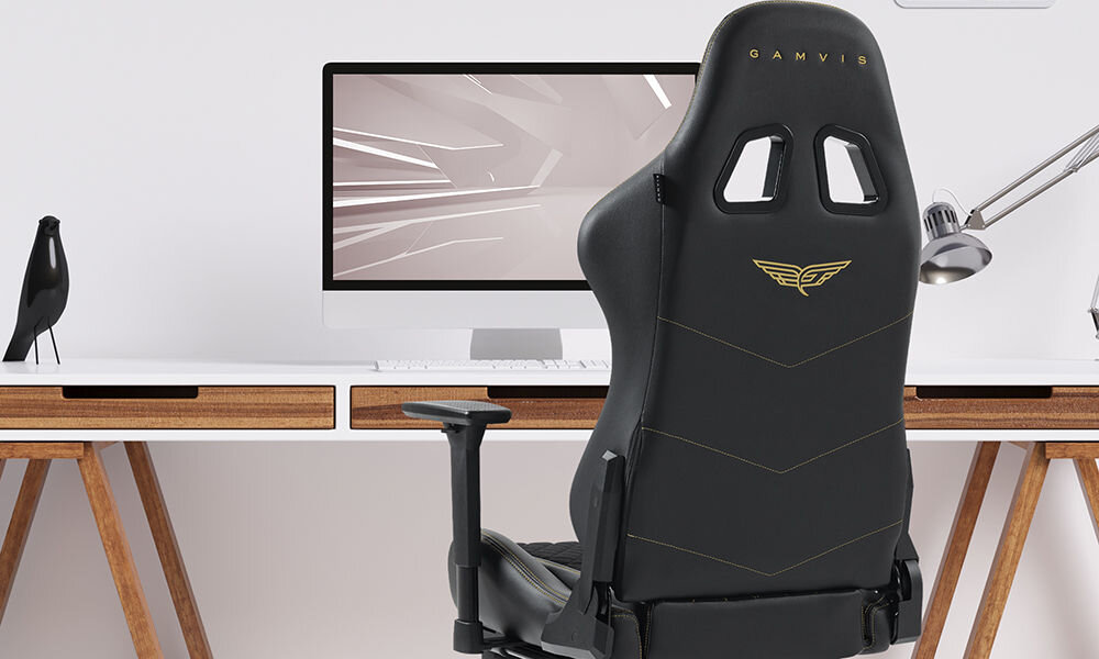 Fotel GAMVIS Phantom Large Czarny (złote elementy) + podnóżek prezentacja fotela w pokoju przy biurku jasna ściana monitor lampka akcesoria wyścigowy charakter elegancja fotel klasy premium niezliczone godziny przed ekranem