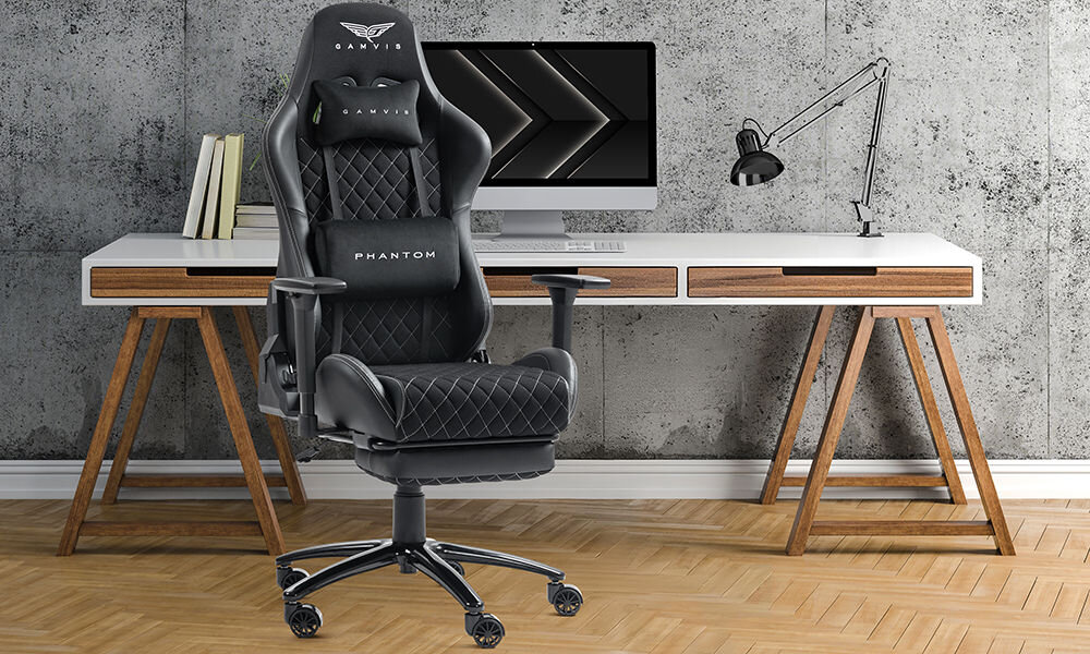 Fotel GAMVIS Phantom Large Czarny (białe elementy) + podnóżek prezentacja fotela na tle pokoju w tle biurko z monitorem i akcesoriami szara ściana imitująca beton wielozadaniowy komfort biuro