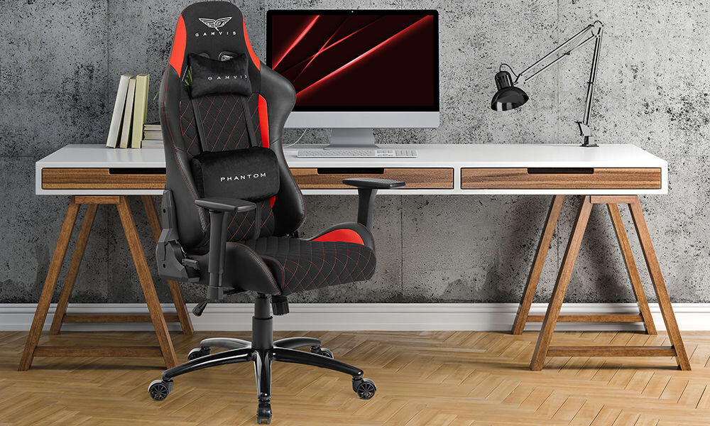 Fotel GAMVIS Phantom Large Czarny (czerwone elementy) prezentacja fotela na tle pokoju w tle biurko z monitorem i akcesoriami szara ściana imitująca beton wielozadaniowy komfort biuro
