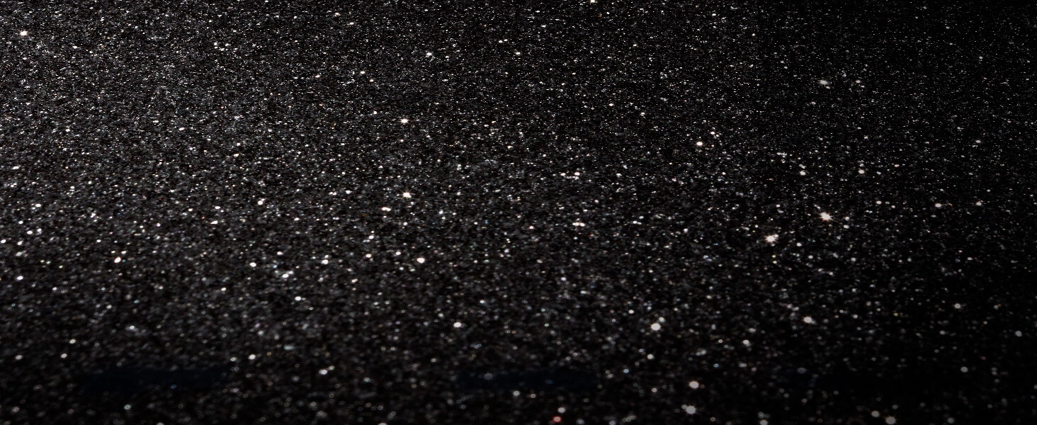 Tło z czarnego, błyszczącego brokatu, pełne małych, jasnych refleksów światła, przypominające gwiezdną noc.