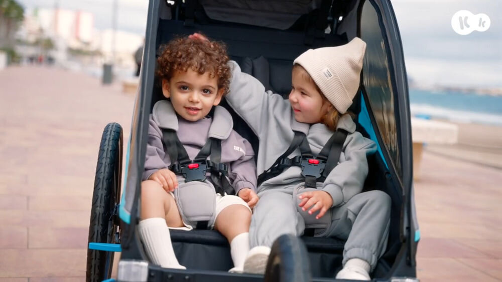 Przyczepka rowerowa KINDERKRAFT Nava 3w1 Pomarańczowy przyczepka na białym tle widoczna z boku dyszel podłączony do koła rowerowego błyskawiczny montaż dzięki klikowym mocowaniom łatwe podłączenie do roweru możliwość przejazdu przez standardowe drzwi