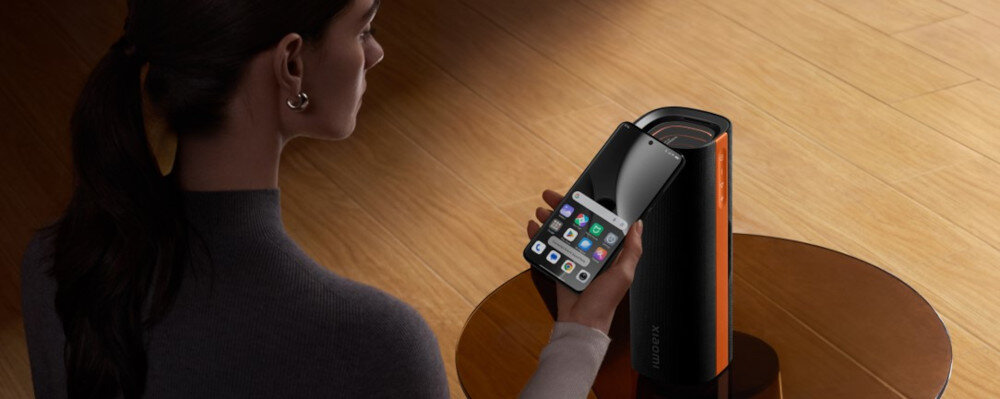 Głośnik mobilny XIAOMI Sound Party, LED, efekty świetlne synchronizowane z muzyką, osoba trzymająca smartfon w ręku , głosnik stojący na stoliku na sztorc