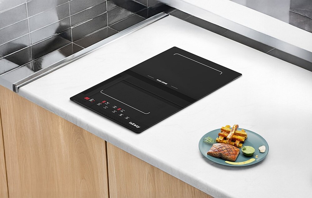 Płyta indukcyjna ISEASY LI2V-15 Płyta indukcyjna jest osadzona w blacie, a obok niej ustawiono talerz z mięsem i warzywami. Panel sterowania jest wyraźnie widoczny i podkreśla funkcjonalność urządzenia Flex Zone elastyczne pole grzewcze