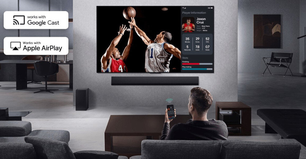 Telewizor LG 43UA75006LA UHD 4K α7 AI Gen8 Multi View podział ekranu Google Cast AirPlay jednocześnie dwa źródła, osoba siedząca na kanapie z smartfonem w ręku, telewizor z soundbarem powieszony na ścianie