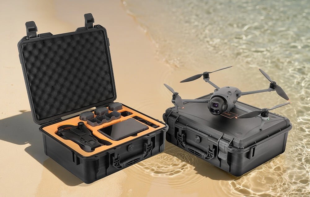 Na obrazie widoczny jest otwarty futerał z wyciętymi miejscami na drona i akcesoria oraz dron umieszczony na zamkniętym futerale, na tle piaszczystej plaży.