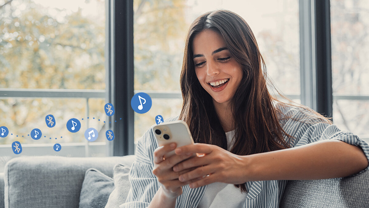 Soundbar SHARP HT-SBW312 Bluetooth 5.3, bezprzewodowe odtwarzanie, smartfon, tablet, osoba siedząca na kanapie z telefonem w ręku