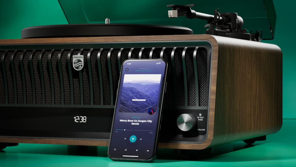 Gramofon PHILIPS TAV9000D/10 radio DAB FM Bluetooth LC3 Auracast, gramofon po skosie wraz z smartfonem na zielonym tle