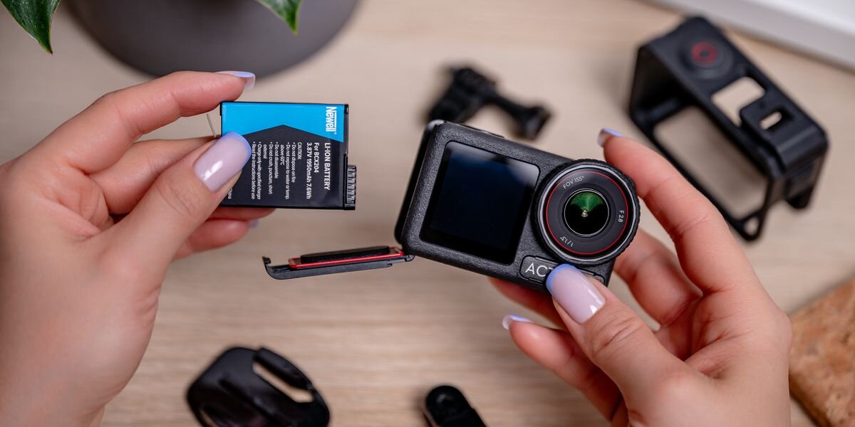 Akumulator NEWELL zamiennik BCX204 do DJI Osmo Action 3/4/5 Pro, Dłonie z pomalowanymi paznokciami wkładające czarno-niebieski akumulator Newell do otwartej komory kamery sportowej, szybkie, bezpamięciowy, napięcie, gotowy