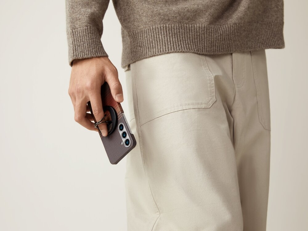 Etui PITAKA Ultra-Slim MagSafe
                telefon z etui trzymany w dłoni przy uchu na jasnym tle