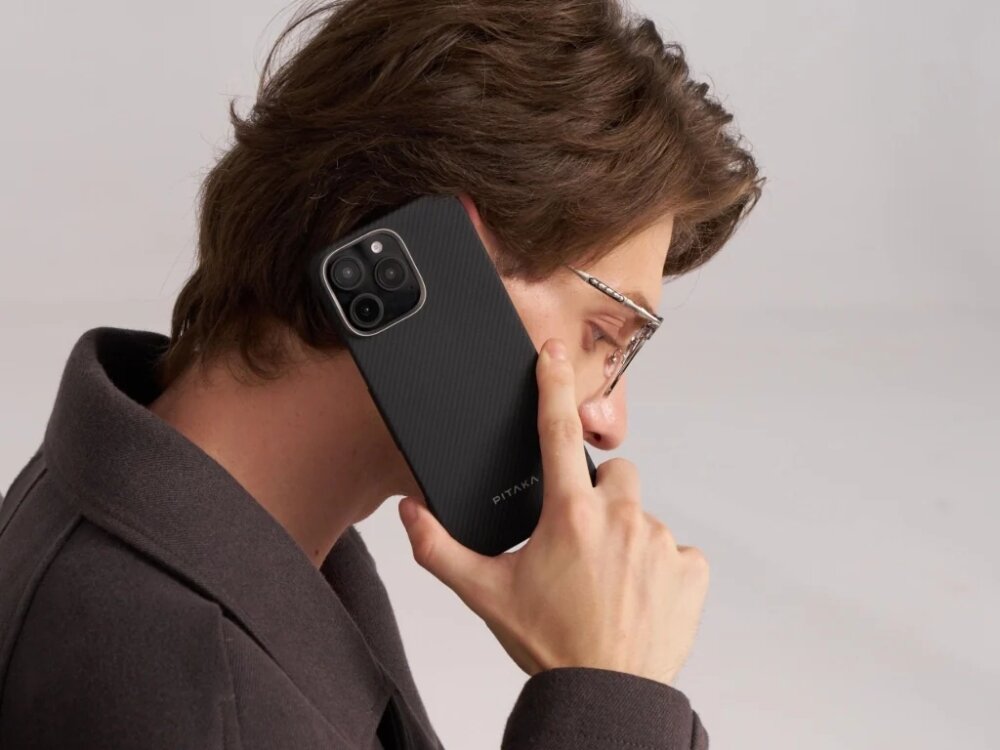 Etui PITAKA Ultra-Slim MagSafe
                telefon z etui trzymany w dłoni przy uchu na jasnym tle